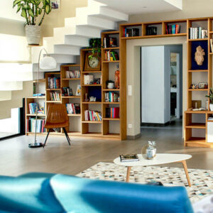 Modern living room with built-in wooden bookshelves under a staircase, a coffee table, and contemporary decor.