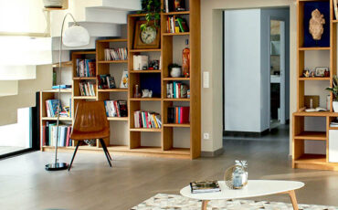 Modern living room with built-in wooden bookshelves under a staircase, a coffee table, and contemporary decor.