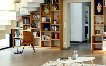 Modern living room with built-in wooden bookshelves under a staircase, a coffee table, and contemporary decor.