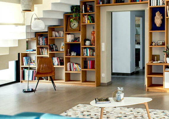 Modern living room with built-in wooden bookshelves under a staircase, a coffee table, and contemporary decor.