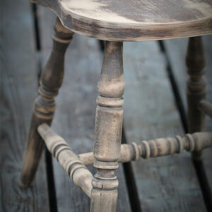 Close-up of a worn wooden chair with visible aged texture and carved legs.