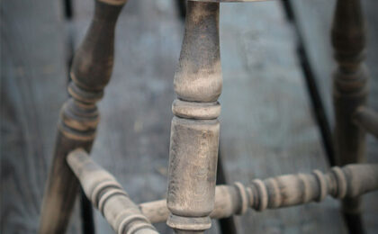Close-up of a worn wooden chair with visible aged texture and carved legs.