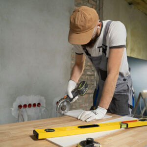 Construction worker using a power tool to cut material on a workbench during home renovation.