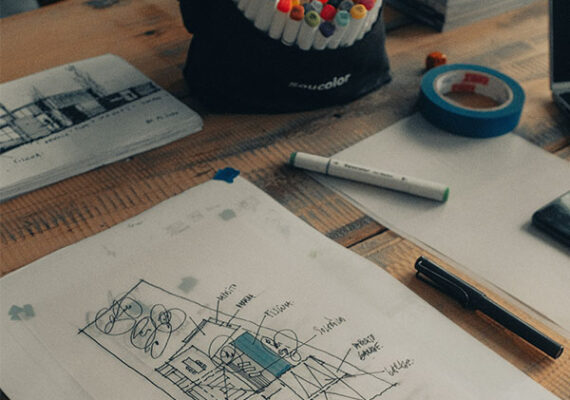 Architectural sketch on a desk with markers, tape, and design tools.